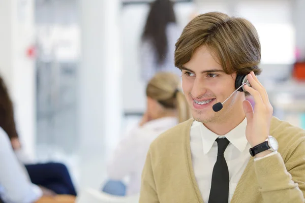 Lachende jongeman in callcenter — Stockfoto