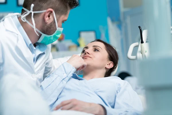 Tandarts onderzoeken patiënt tanden met een mondspiegel. — Stockfoto
