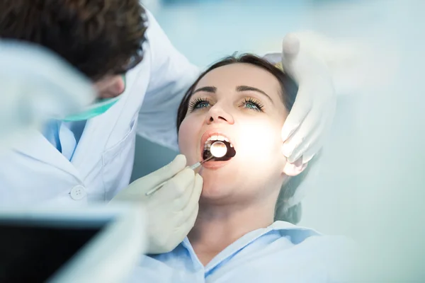Zubař zkoumání pacientů zuby v ústech zrcadlem. — Stock fotografie