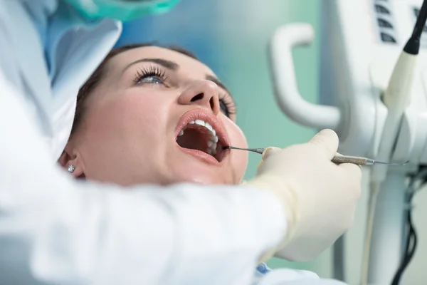 Dentiste examinant les dents du patient avec un miroir buccal . — Photo