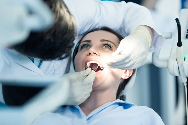 Tandarts onderzoeken patiënt tanden met een mondspiegel. — Stockfoto