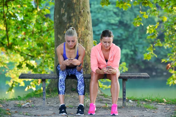 Duas mulheres fazendo pausa usando o telefone — Fotografia de Stock