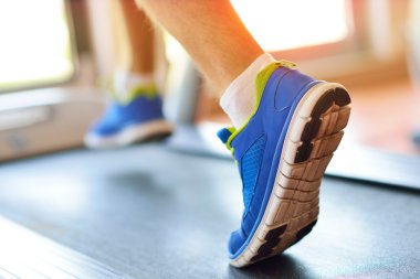 Spor salonunda koşu bandında koşan bir adam. 