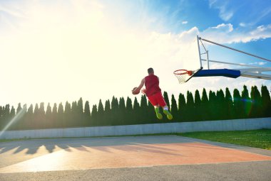 RIM bir slam dunk için doğru uçan bir genç basketbolcu.