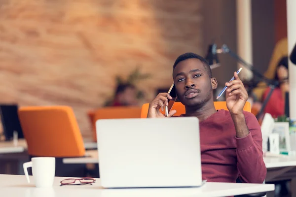 Uomo d'affari al telefono seduto al computer — Foto Stock