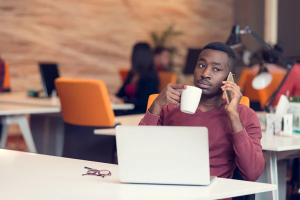 Uomo d'affari al telefono seduto al computer — Foto Stock