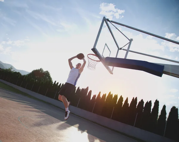 Young man jumping and making a fantastic slam dunk playing stree — Stockfoto