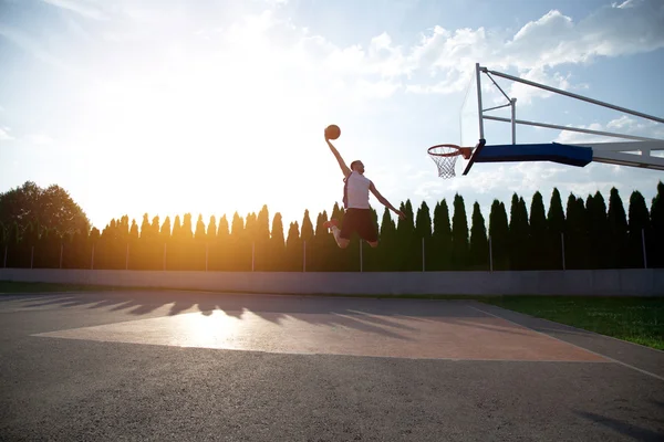 Young man jumping and making a fantastic slam dunk playing stree — Stock fotografie