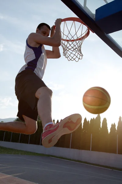 Young man jumping and making a fantastic slam dunk playing stree — Stockfoto