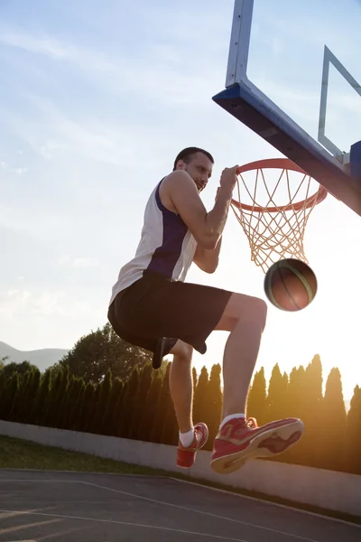 Young man jumping and making a fantastic slam dunk playing stree — Stock fotografie