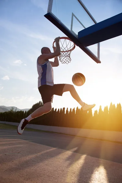 Junger Mann springt und macht einen fantastischen Slam Dunk beim Stree spielen — Stockfoto