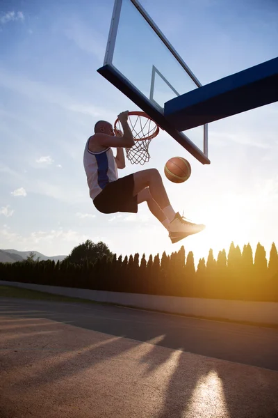 Young man jumping and making a fantastic slam dunk playing stree — ストック写真