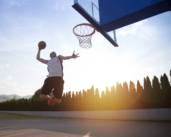 Young man jumping and making a fantastic slam dunk playing stree — Stockfoto