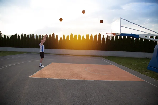 Ein groß gewachsener Mann, der sich darauf vorbereitet, in einem Park einen Basketball zu schießen — Stockfoto