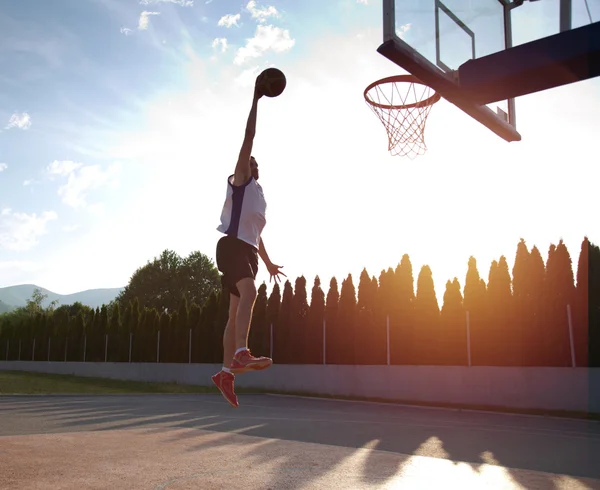 Young man jumping and making a fantastic slam dunk playing stree — ストック写真