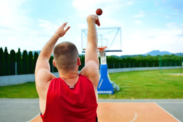 Vista trasera de un jugador de baloncesto, disparando a la cesta al aire libre —  Fotos de Stock