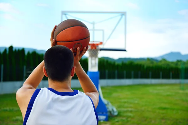 Vista trasera de un jugador de baloncesto, disparando a la cesta al aire libre — Foto de Stock