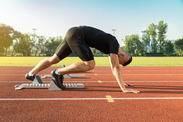 Homme athlétique commence à courir dans les rayons du soleil — Photo