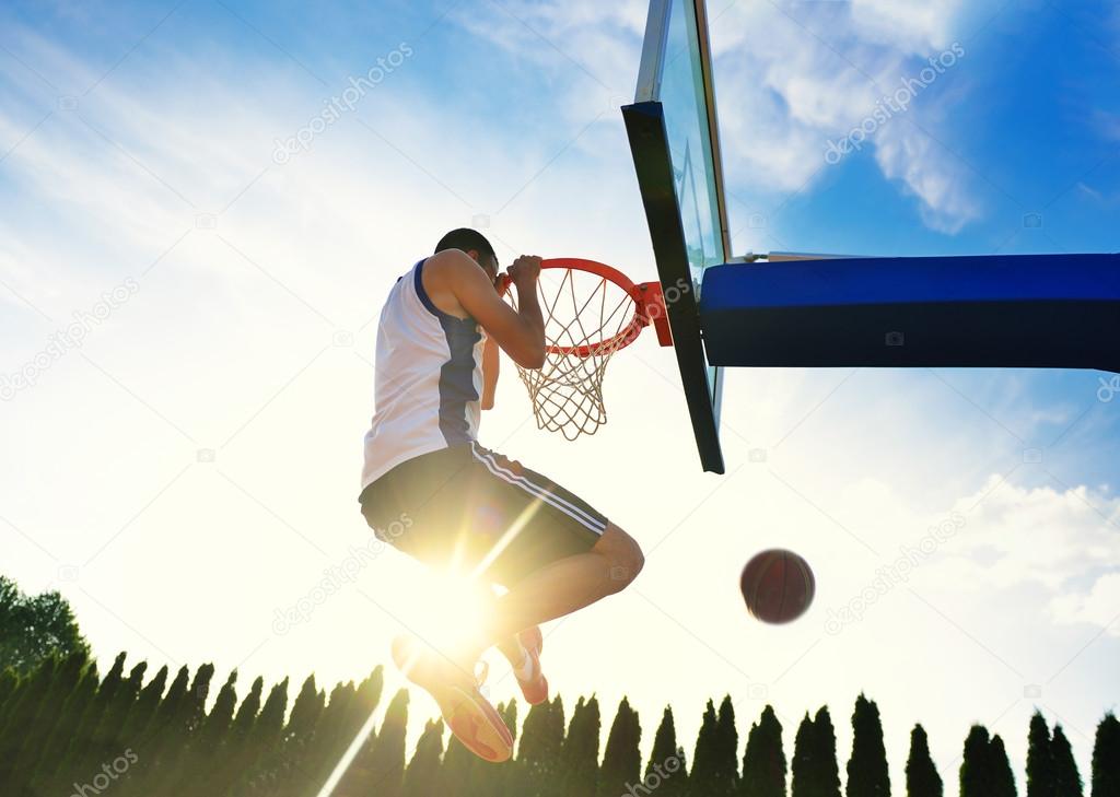 Street basketball player performing power slum dunk.