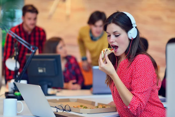 Cheerful office girl enjoying pizza at lunchtime — Stock Photo, Image