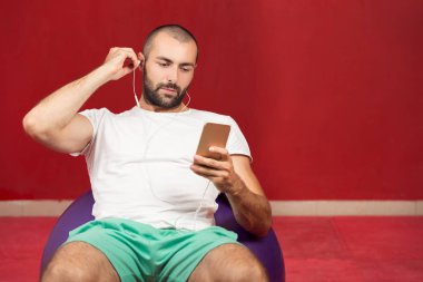 man sitting on a gym ball holding a phone  clipart