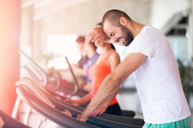 Modern bir spor salonu bir koşu bandı üzerinde çalışan adam.