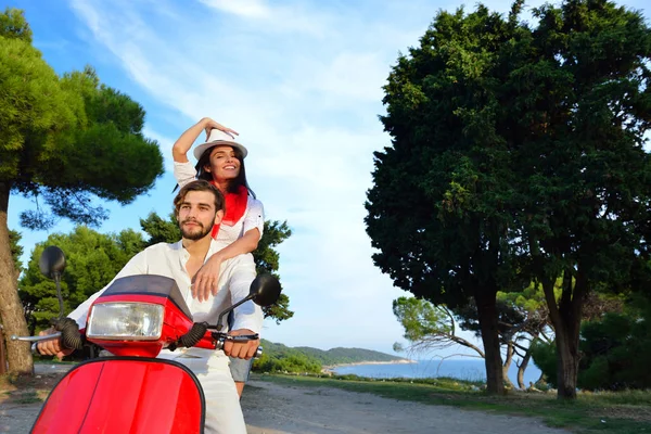 Hermosa pareja joven montando en un scooter — Foto de Stock