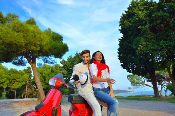 Glückliches junges Paar auf Motorroller in einem Park — Stockfoto