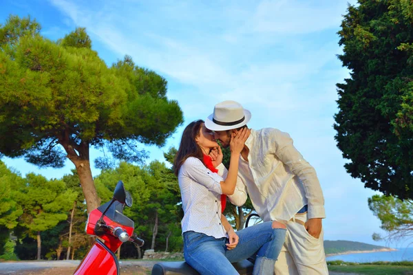 Glückliches junges Paar auf Motorroller in einem Park — Stockfoto