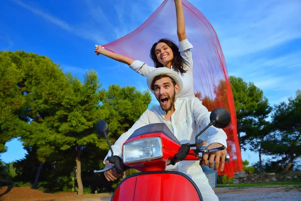 Hermosa pareja joven montando en un scooter — Foto de Stock