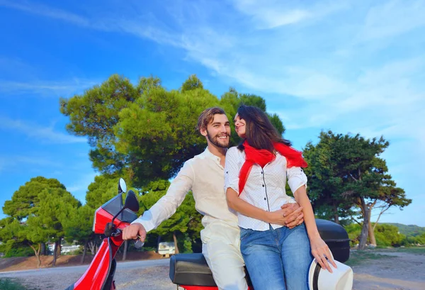 Glückliches junges Paar auf Motorroller in einem Park — Stockfoto