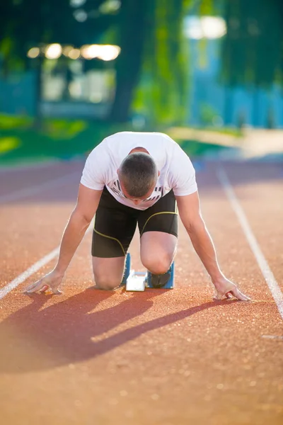 Hombre atlético en pista comenzando a correr . — Foto de Stock