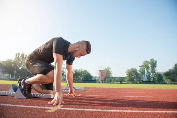 Atleta di sesso maschile in posizione di partenza sulla pista di atletica . — Foto Stock