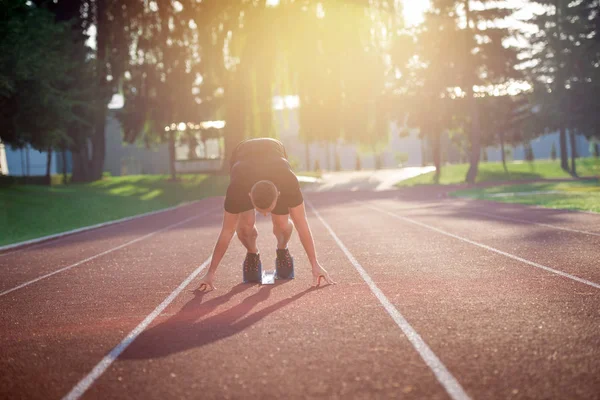 Athletic man on track starting to run.