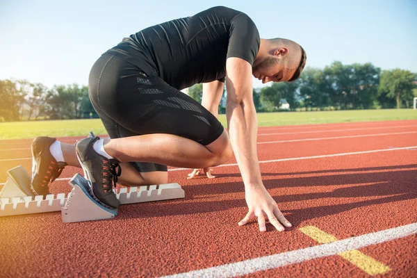 Atleta di sesso maschile in posizione di partenza sulla pista di atletica . — Foto Stock