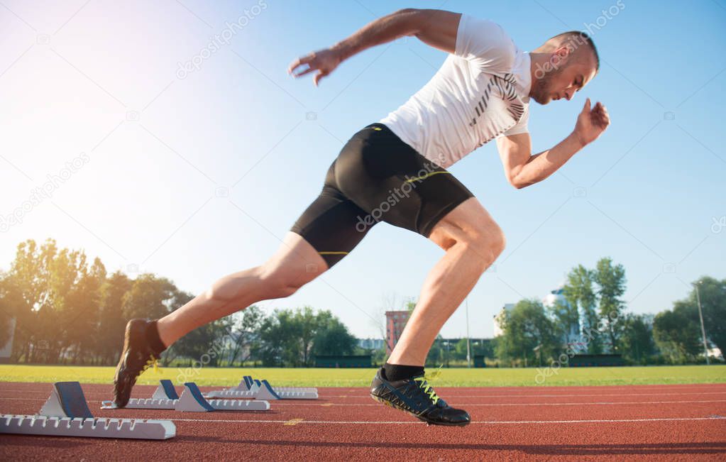 Athletic man on track starting to run. 