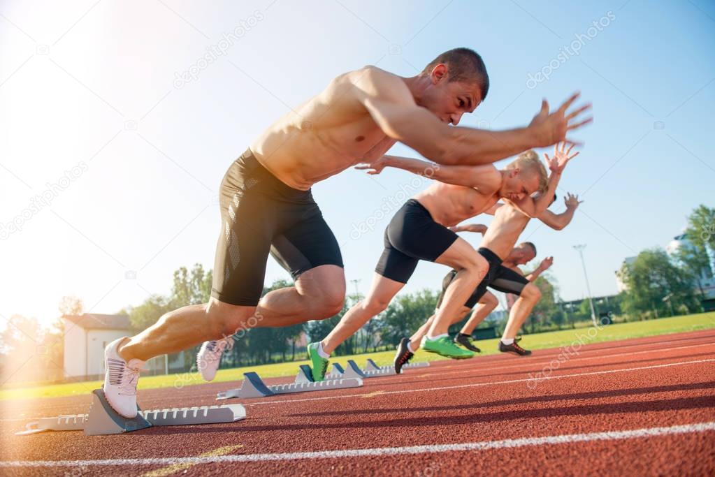 Male athletics runners on starting line 