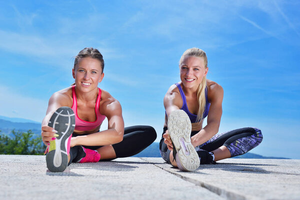 Two pretty women stretching in a park