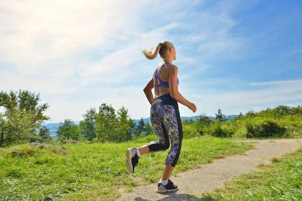 Chica joven corredora trotando en un sendero de montaña — Foto de Stock