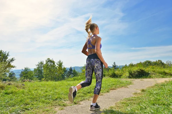 Chica joven corredora trotando en un sendero de montaña — Foto de Stock