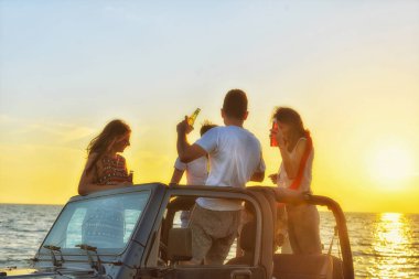 Gençler plajda arabada eğleniyorlar. 