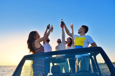 Gençler plajda arabada eğleniyorlar. 