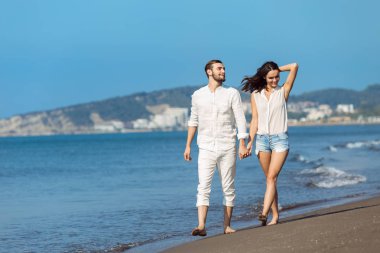 Plaj gülümseyerek yürüyen genç Çift 