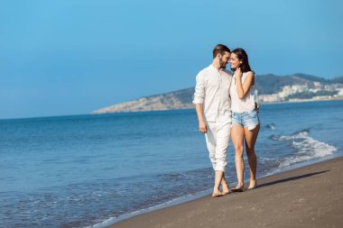 Plaj gülümseyerek yürüyen genç Çift 