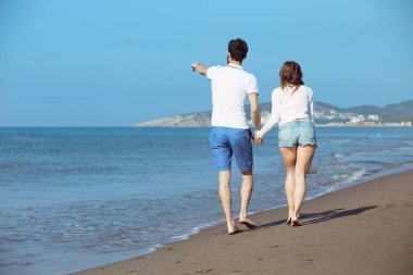 Genç bir çift sahilde yürüyor. 