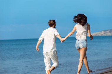 Plaj gülümseyerek yürüyen genç Çift 