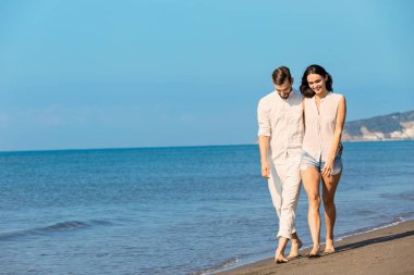 Plaj gülümseyerek yürüyen genç Çift 