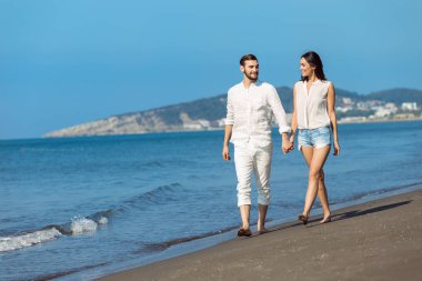 Plaj gülümseyerek yürüyen genç Çift 