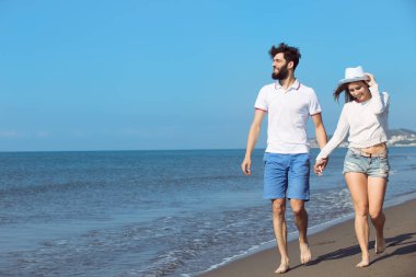 Genç bir çift sahilde yürüyor. 