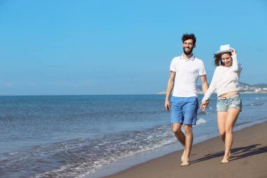 Genç bir çift sahilde yürüyor. 